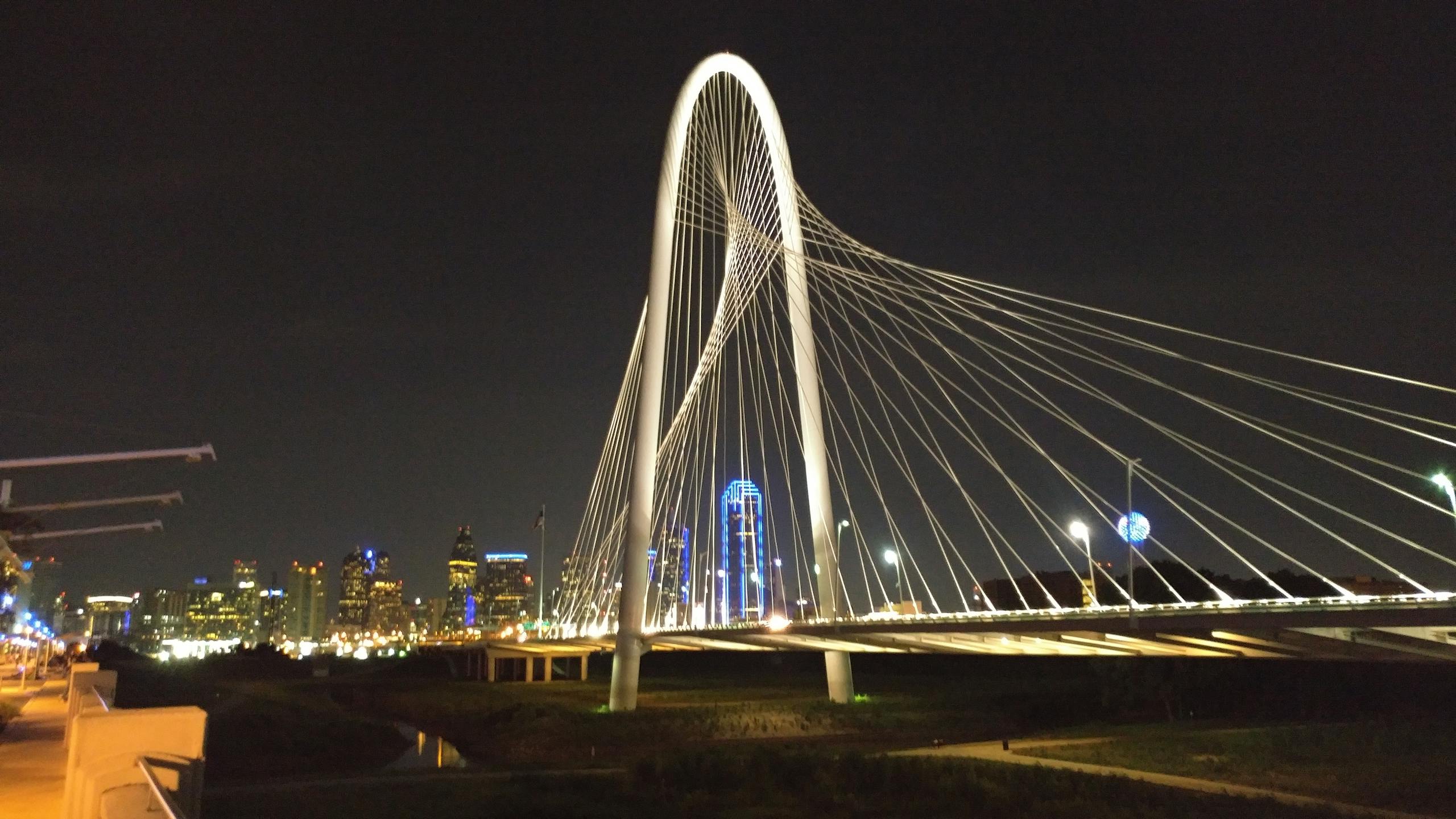Iconic Dallas skyline featuring the illuminated Margaret Hunt Hill Bridge at night.